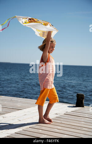 Una ragazza su un molo tenendo un aquilone, Svezia. Foto Stock