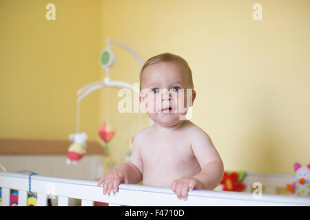 11 mese vecchio ragazzo caucasico, sorge nella sua culla, London, England, Regno Unito Foto Stock