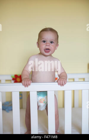 11 mese vecchio ragazzo caucasico, sorge nella sua culla, London, England, Regno Unito Foto Stock