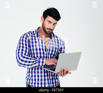 Ritratto di un uomo bello utilizzando computer portatile isolato su uno sfondo bianco e guardando la fotocamera Foto Stock