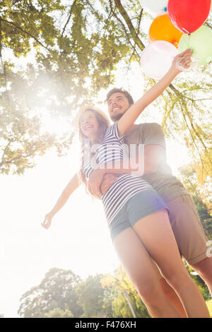 Carino coppia abbracciando e palloncini di contenimento nel parco Foto Stock