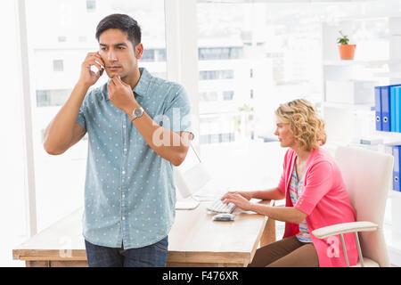 Uomo concentrato in posa davanti al suo collega con il cellulare Foto Stock