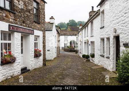 Case imbiancate a calce e strada di ciottoli nel villaggio di ammaccatura, Dentdale, Cumbria, Regno Unito Foto Stock