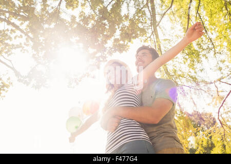 Carino coppia abbracciando e palloncini di contenimento nel parco Foto Stock