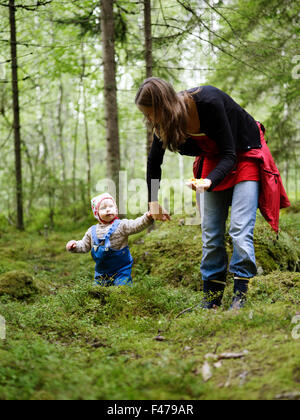 Una donna con un bambino piccolo la raccolta di funghi, Svezia. Foto Stock