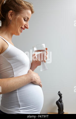 Donna incinta con un drink Foto Stock