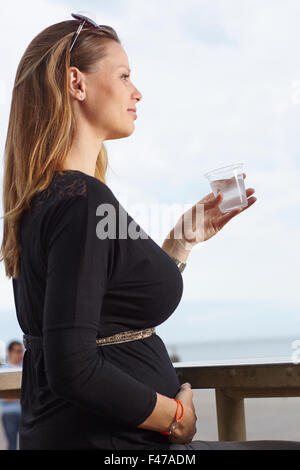 Donna incinta con un drink Foto Stock