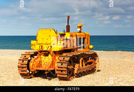 Un vecchio giallo caterpillar di lavoro trattore usato per il traino di barche da pesca a Cley-next-il-Mare, Norfolk, Inghilterra, Regno Unito. Foto Stock