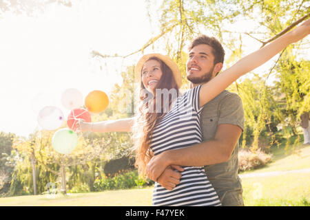 Carino coppia abbracciando e palloncini di contenimento nel parco Foto Stock