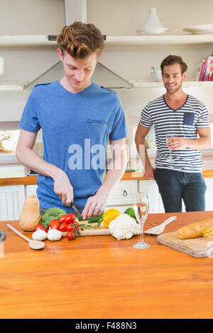 Uomo felice come tagliare le verdure in cucina con il mio ragazzo dietro Foto Stock