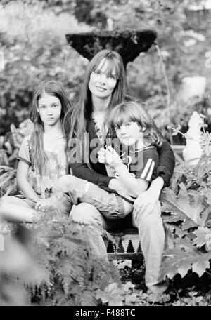 Donna con i suoi due bambini in un giardino. Foto Stock