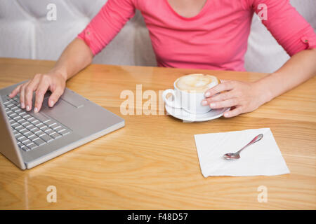 Donna con un caffè utilizzando laptop Foto Stock