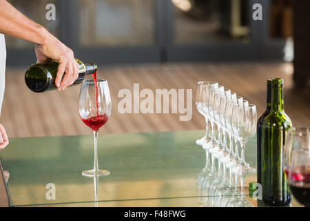 L'uomo versando il vino rosso in un bicchiere Foto Stock
