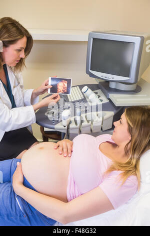 Medico che mostra immagini per la donna in stato di gravidanza Foto Stock