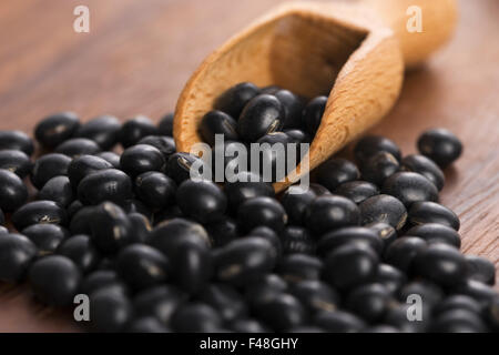 Un sacco di fagioli di soia nera su sfondo di legno Foto Stock