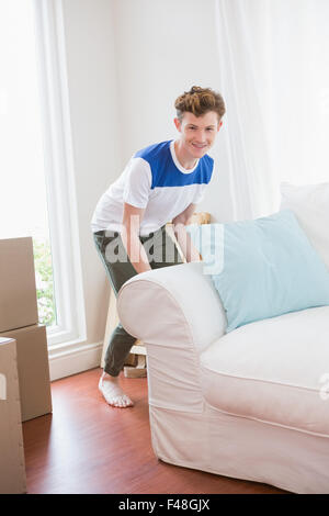 Felice giovane divano di sollevamento a casa Foto Stock