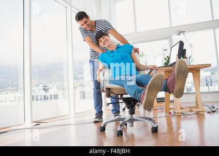 Sorridendo gli editor di foto per divertirsi su una sedia girevole Foto Stock