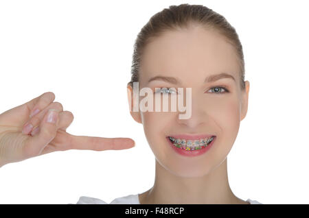 Sorridente ragazza felice indica le bretelle sui denti Foto Stock