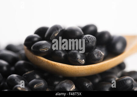 Un sacco di fagioli di soia nera su sfondo di legno Foto Stock