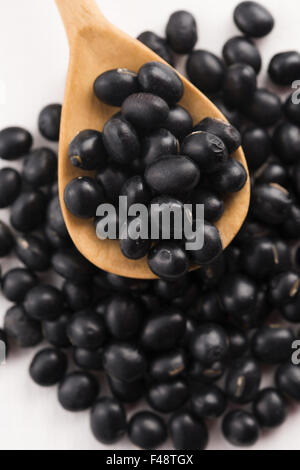 Un sacco di fagioli di soia nera su sfondo di legno Foto Stock
