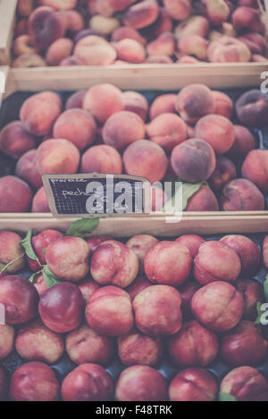 Mature di pesche fresche in un mercato degli agricoltori. Filtrata girato con una messa a fuoco selettiva Foto Stock