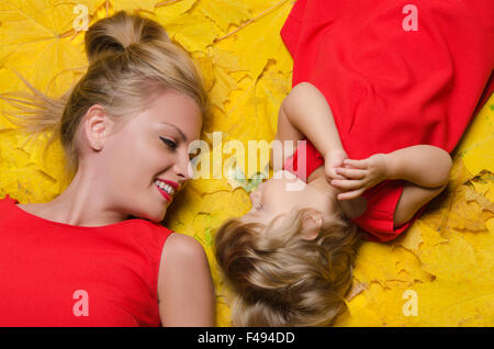 Bella donna e bambino in foglie di autunno Foto Stock