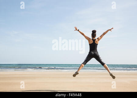 Montare la donna salta sulla sabbia Foto Stock