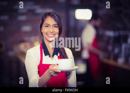 Sorridente cameriera di consegnare una tazza di caffè Foto Stock