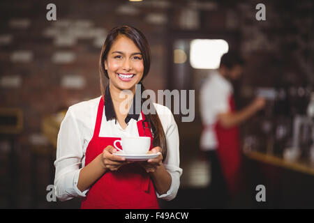 Sorridente cameriera tenendo una tazza di caffè Foto Stock