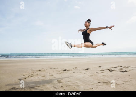 Montare la donna salta sulla sabbia Foto Stock