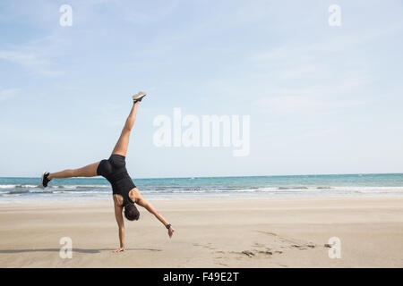 Montare donna cartwheeling sulla sabbia Foto Stock