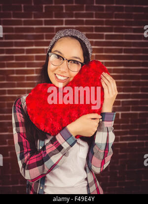 Attraente giovane donna tenendo premuto fino a forma di cuore cuscino Foto Stock