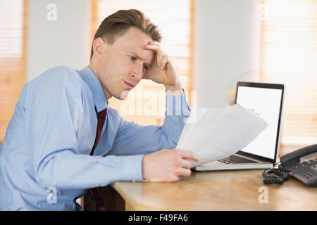 Imprenditore focalizzato la lettura documento alla scrivania Foto Stock