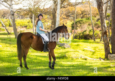 Giovane donna in sella il suo cavallo Foto Stock