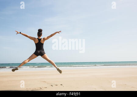 Montare la donna salta sulla sabbia Foto Stock