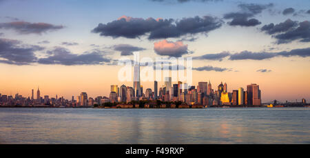 La parte inferiore di Manhattan grattacieli, il quartiere finanziario e Ellis Island panorama al tramonto, New York City, Stati Uniti d'America Foto Stock