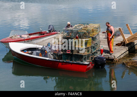 Caricamento dei pescatori Lobster Pot su di una piccola imbarcazione da un galleggiante dock in legno Harpswell Sound Maine USA Foto Stock