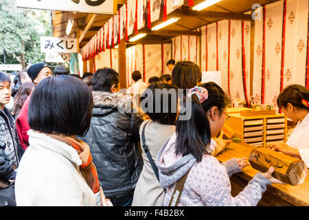 Giappone, Nishinomiya santuario, anno nuovo giorno, Shogatsu. Donna acquisto omikuji fortune paper da Miko, santuario maiden, al santuario di occupato ufficio, Shamusho. Foto Stock