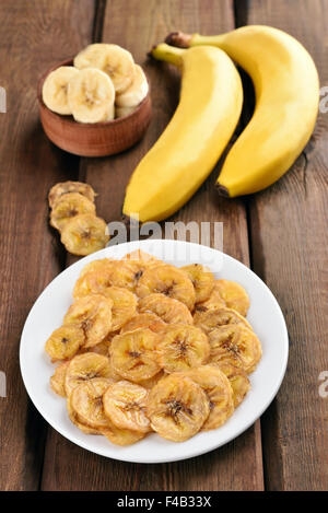 Chip e banane fresche sul tavolo di legno Foto Stock