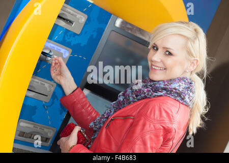 Donna sorridente inserendo la sua carta in un bancomat Foto Stock