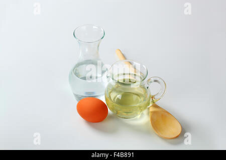 Caraffa di acqua fredda, brocca di olio di semi di girasole, l uovo e il cucchiaio di legno Foto Stock