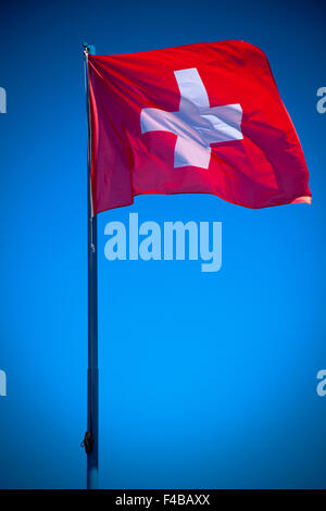 Bandiera svizzera di fronte luminoso cielo blu Foto Stock