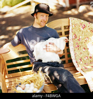 Uomo sorridente tenendo un pollo nelle sue braccia. Foto Stock