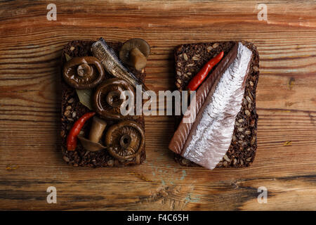 Due diversi sandwich aperto da densa di segale integrale pane (rugbrod) selvaggio con funghi sott'aceto, lo spratto e herrring su invecchiato Foto Stock