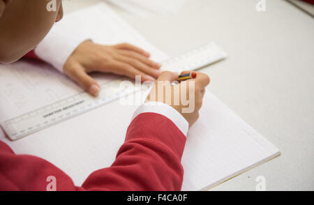 Un tipico UK scuola primaria classe con un alunno il disegno di una linea con un righello Foto Stock