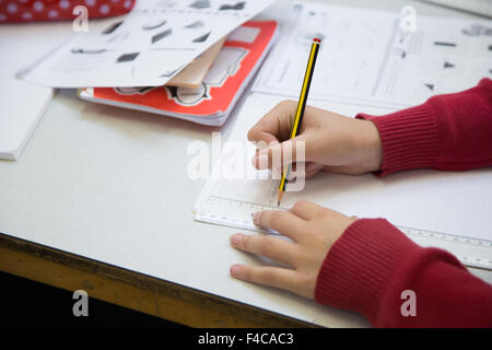 Un tipico UK scuola primaria classe con un alunno il disegno di una linea con un righello Foto Stock