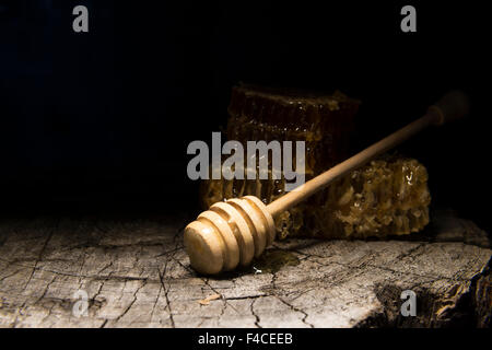 Favi e stick al miele su sfondo di legno Foto Stock