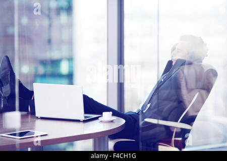 Imprenditore rilassa seduto in ufficio e guardando nella finestra Foto Stock
