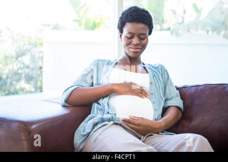 Sorridente donna incinta seduta sul lettino Foto Stock