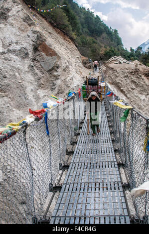 Giovani porter attraversando ponte di sospensione, Nepal. Foto Stock